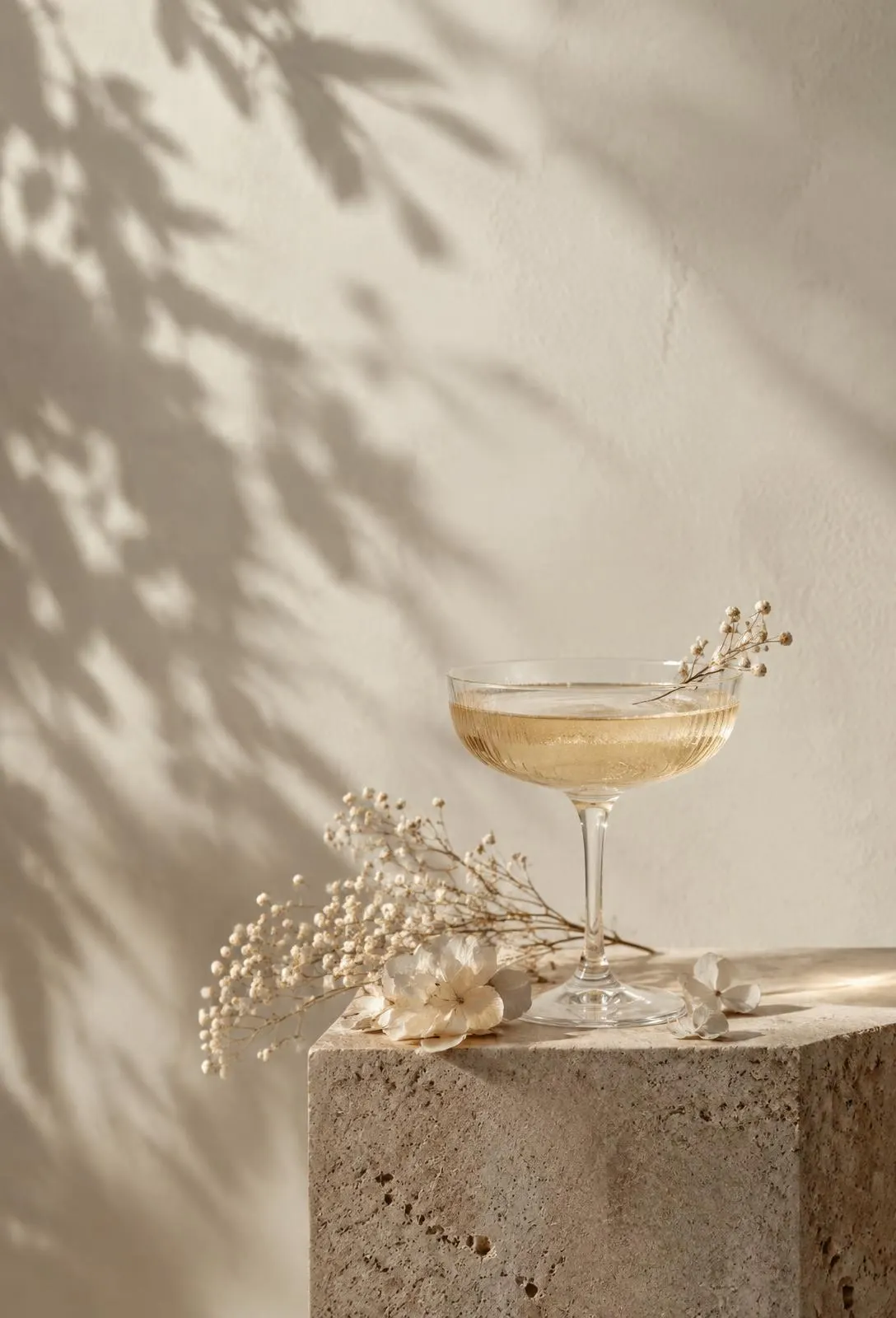 Taça de cristal com espumante sobre pedra travertino e flores secas